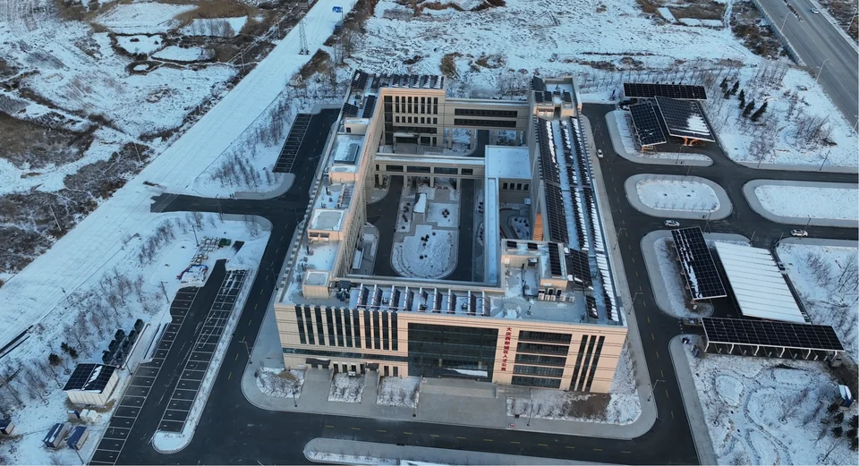 微电网场景航拍实景,展示建筑、屋顶光伏、光伏车棚和周边场地的整体布局